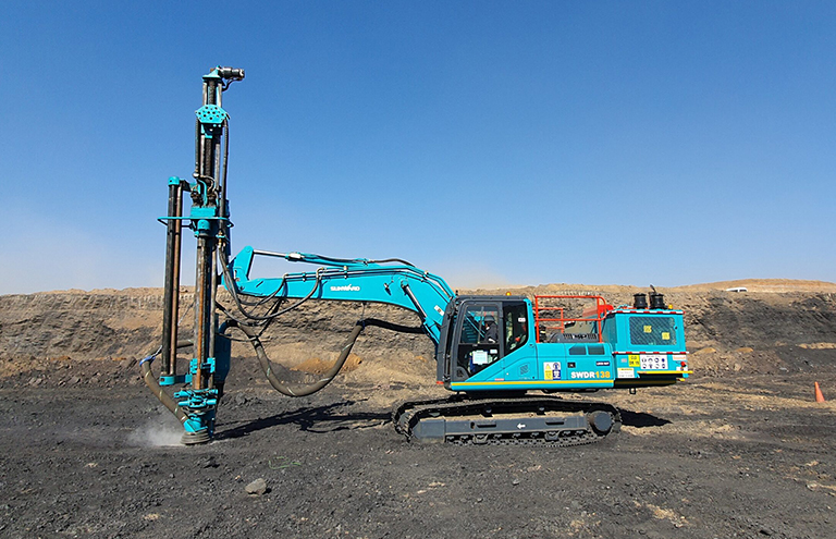 A blue drilling machine actively boring into the soil