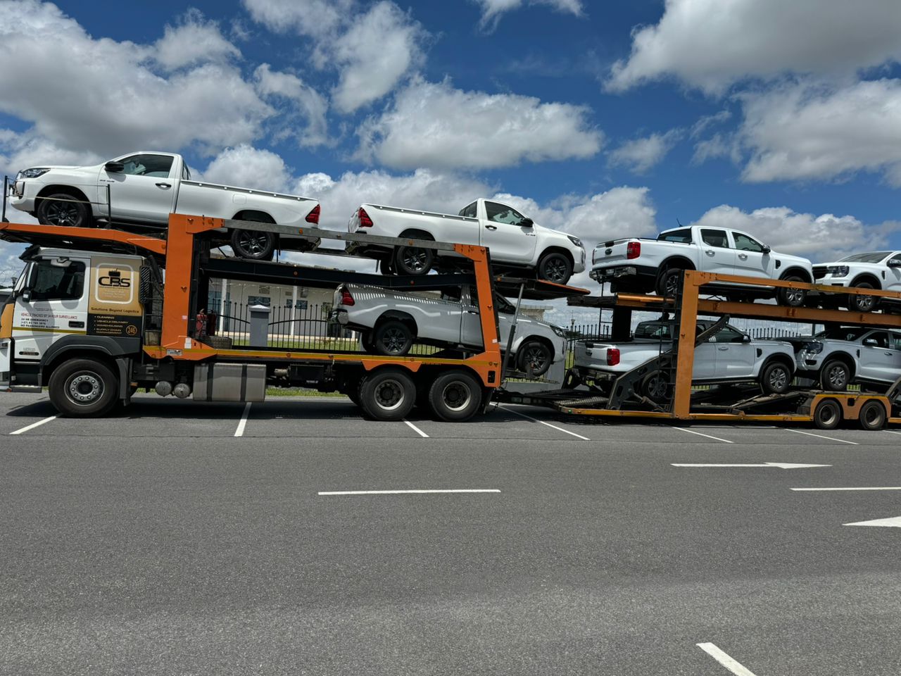 A truck carrying several cars on its back, featuring a diverse selection of vehicles in various colors and designs